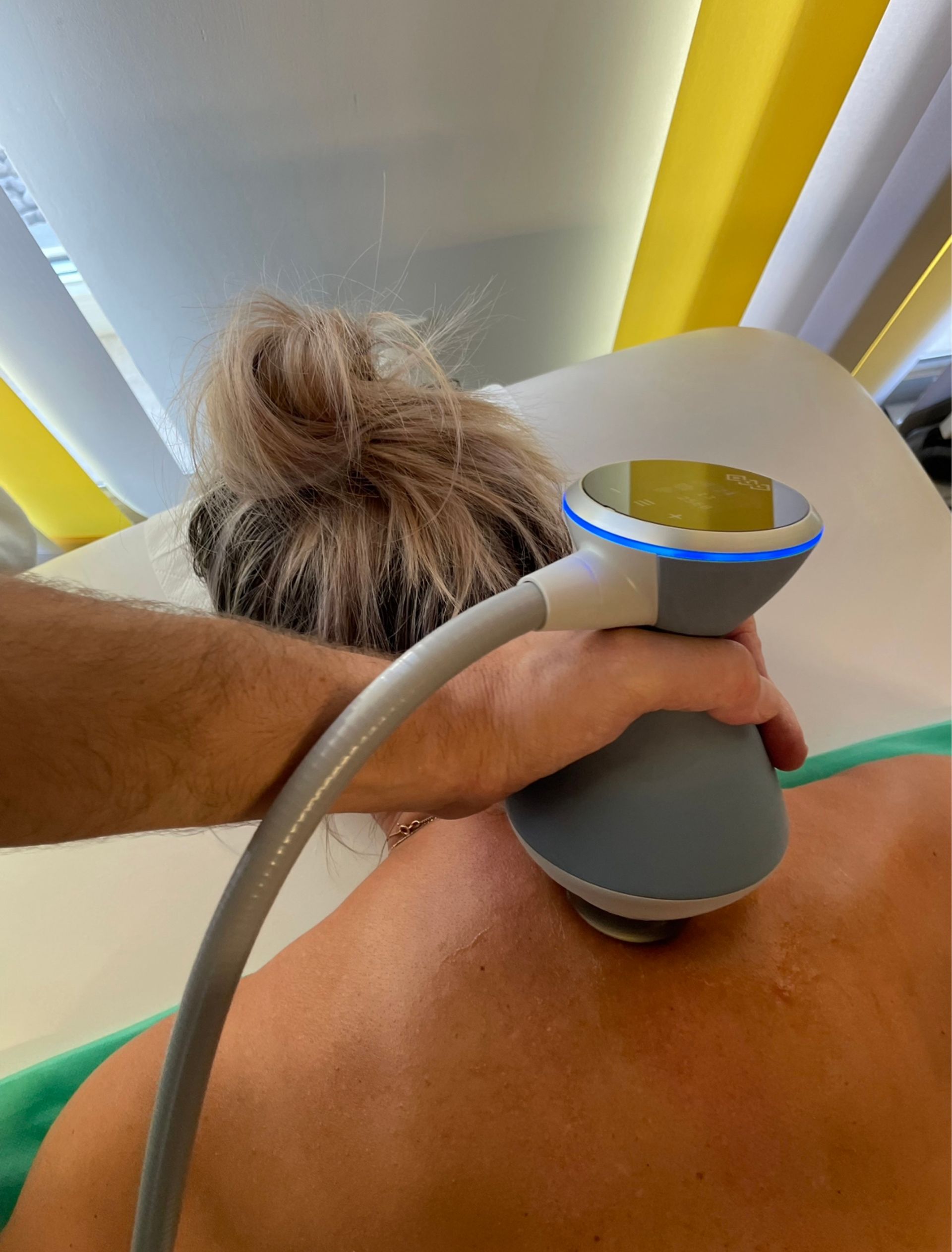 Eine Frau bekommt mit einer Maschine auf ihrem Rücken eine Massage.