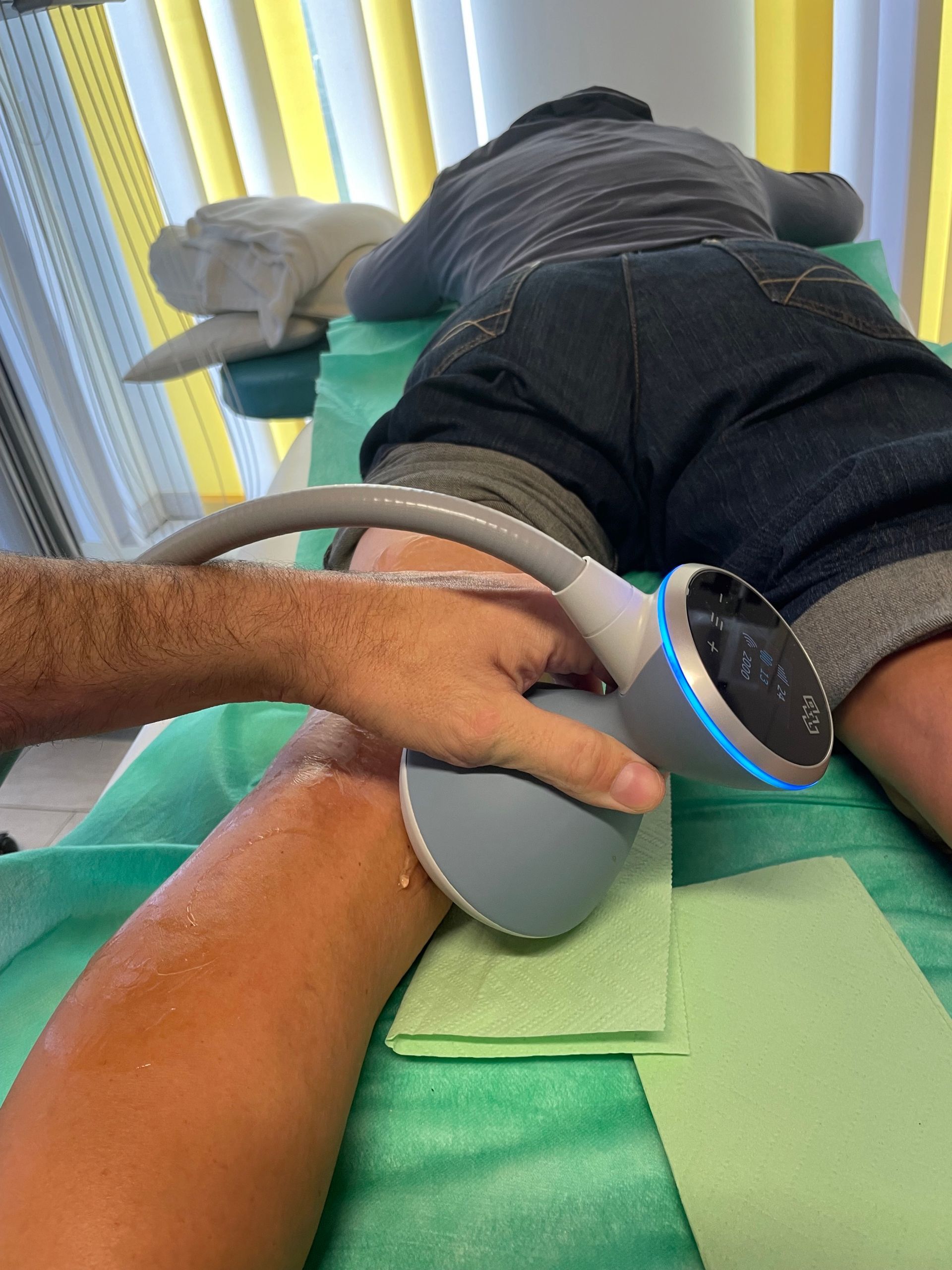 Eine Person liegt mit einer Maschine am Arm auf einem Bett.