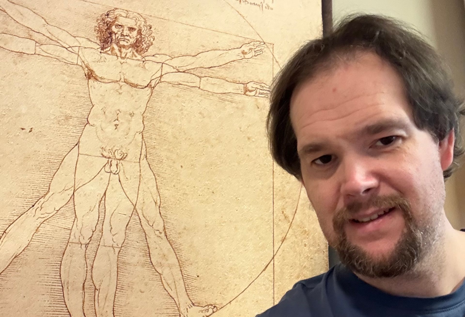 Ein Mann steht vor der Zeichnung eines Mannes mit ausgestreckten Armen.