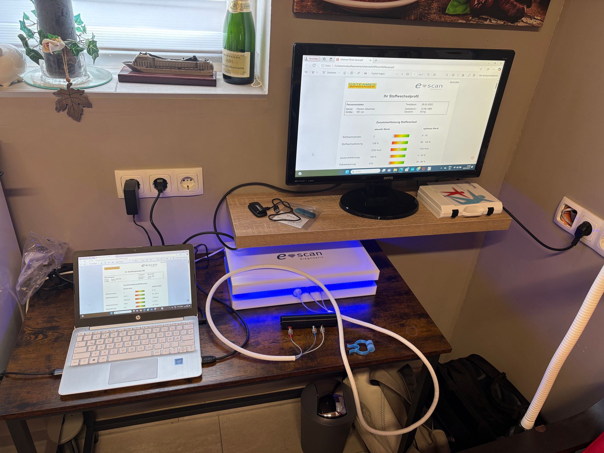 Auf einem Holzschreibtisch steht neben einem Laptop ein Computer.