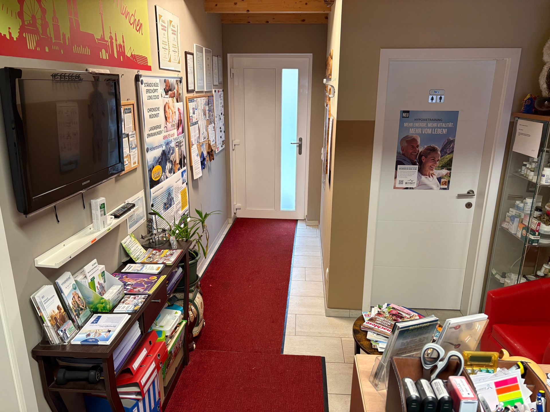 Ein Flur mit einem roten Teppich und einem Fernseher an der Wand