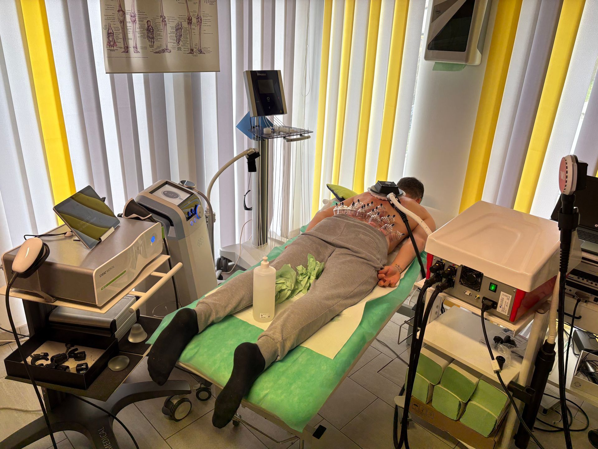 Ein Mann liegt auf einer grünen Couch in einem Raum mit vielen medizinischen Geräten.