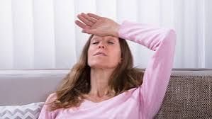 Eine Frau sitzt auf einem Sofa und hat die Hand auf der Stirn.