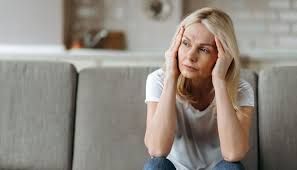 Eine Frau sitzt mit den Händen auf dem Kopf auf einem Sofa.