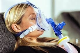 Eine Frau trägt eine Sauerstoffmaske, während sie auf einer Couch liegt.