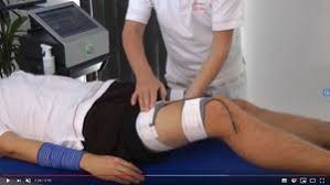 Eine Person liegt auf einem Bett und wird von einem Arzt massiert.