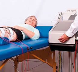 Eine Frau liegt auf einem blauen Tisch, auf dem eine Maschine steht.