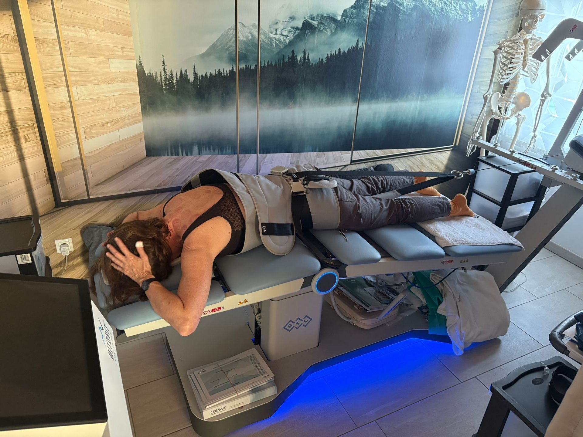 Eine Frau liegt auf einem Tisch, im Hintergrund ist ein Skelett zu sehen.