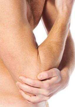 Ein Mann hält sich vor Schmerzen den Ellbogen.