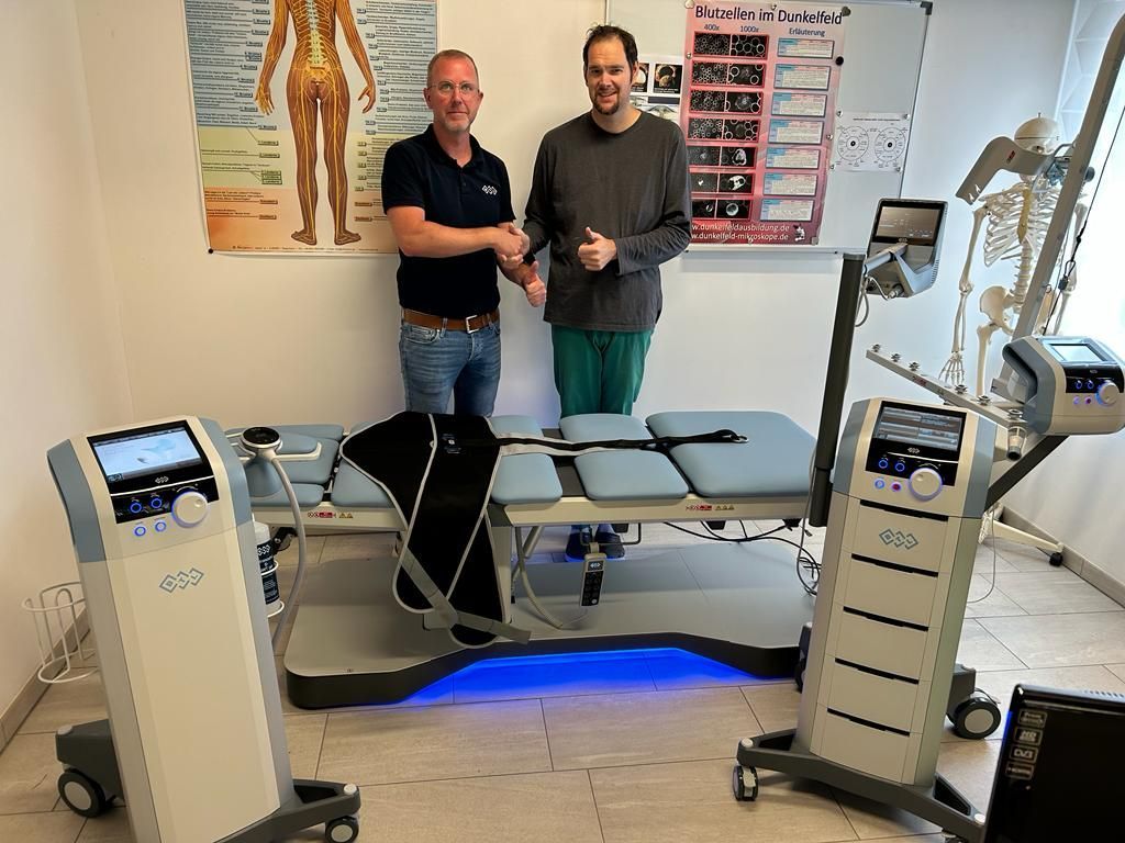 Zwei Männer geben sich in einem Raum mit medizinischen Geräten die Hand.