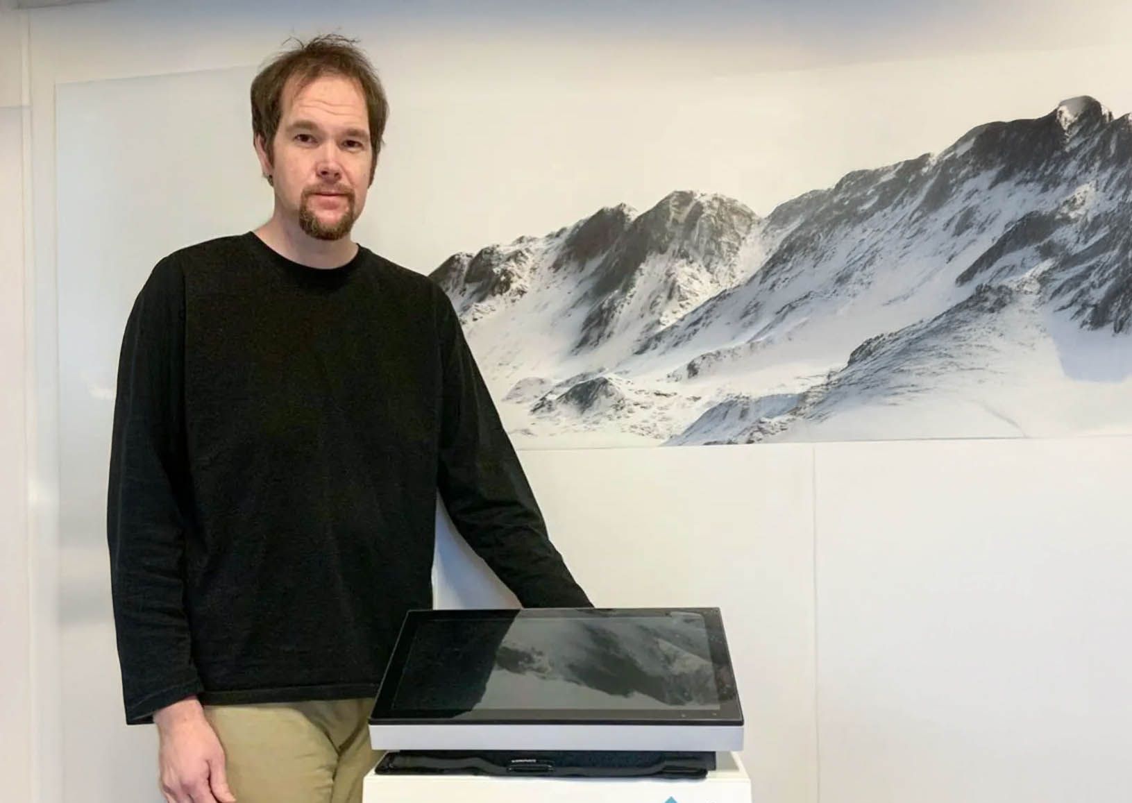 Ein Mann in einem schwarzen Hemd steht neben einem Drucker.