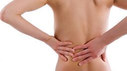 Eine Frau hält sich vor Schmerzen den Rücken.