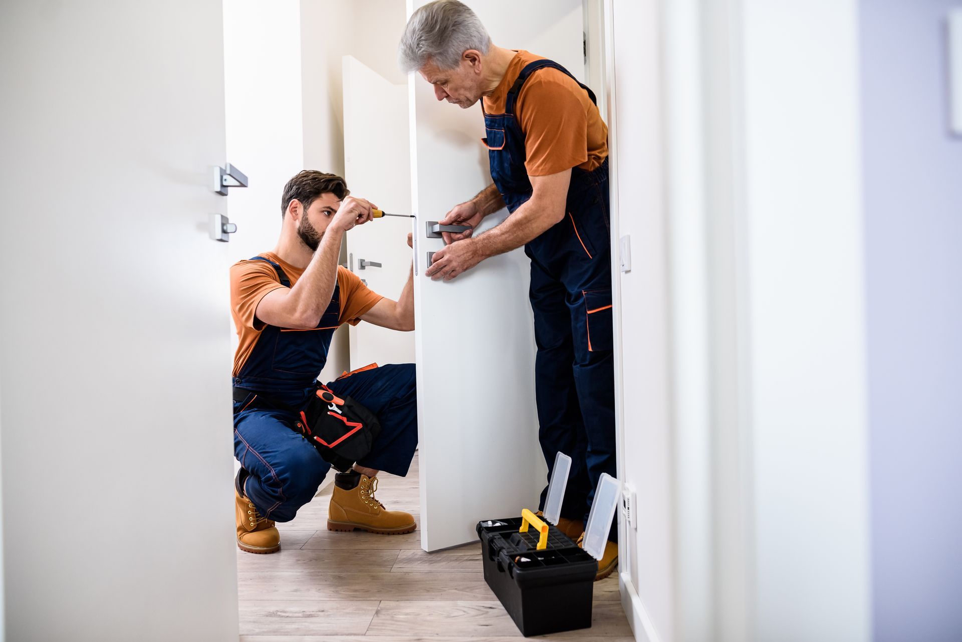 Zwei Männer arbeiten an einer Tür in einem Flur.