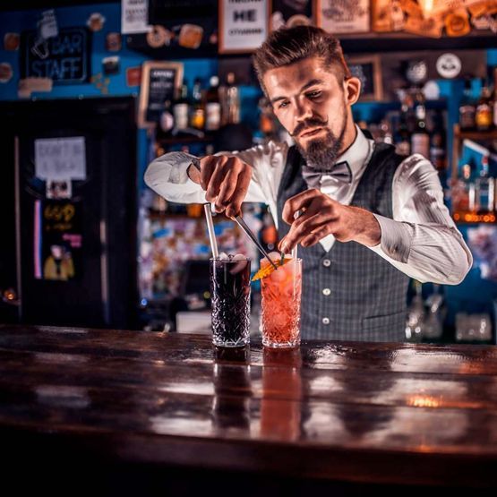 Un camarero está preparando una bebida en un bar.
