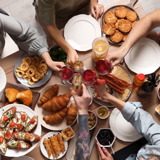 Un grupo de personas están sentadas alrededor de una mesa con platos de comida y bebidas.