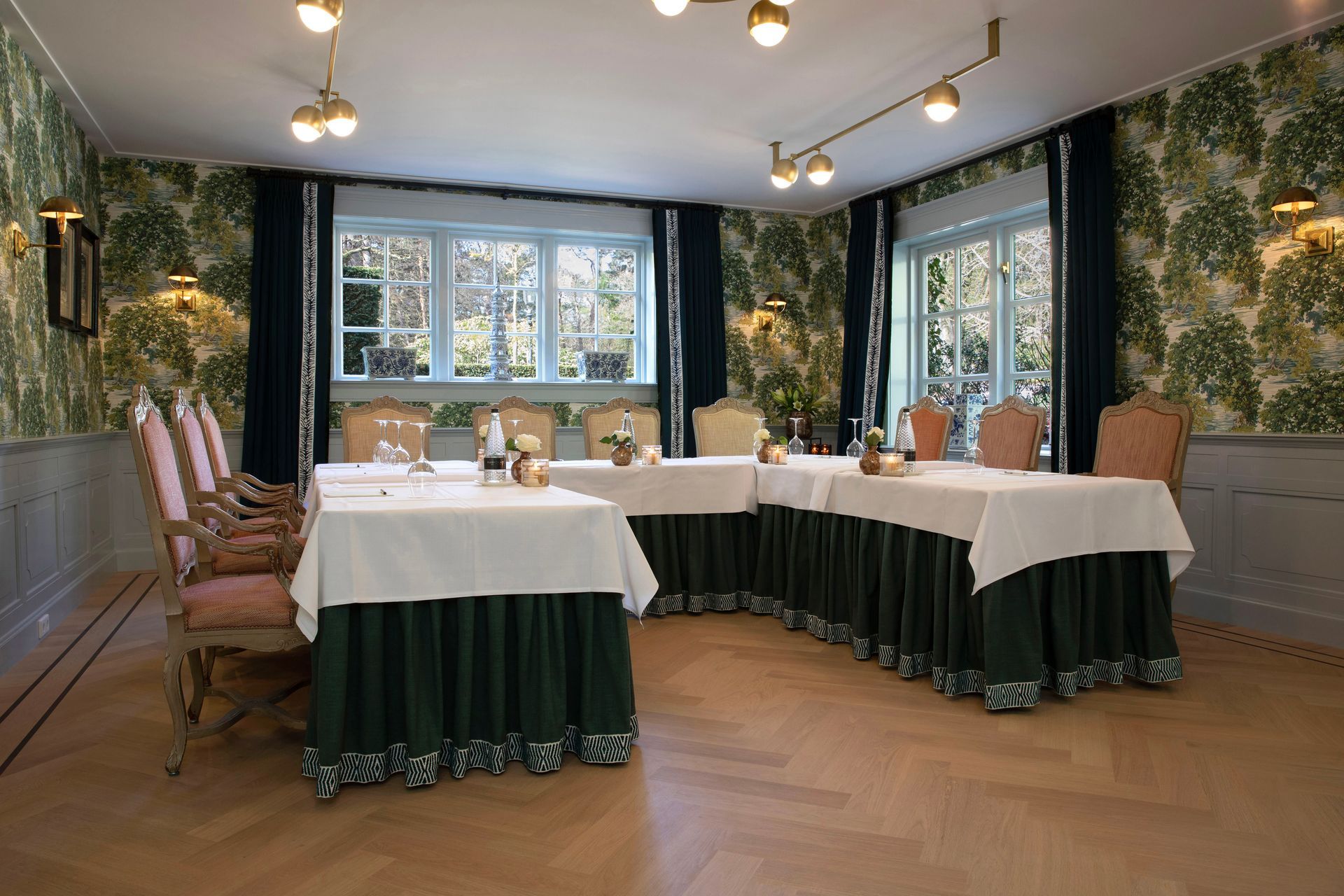 Paarse blauweregenbloemen hangen over een boog die een zonnig terras omlijst, met tafels, stoelen en witte parasols.