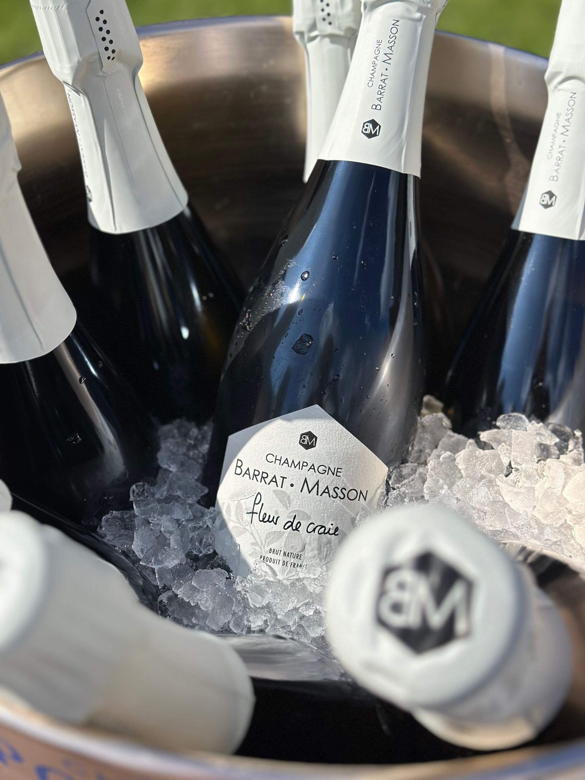 Verschillende flessen mousserende wijn staan ​​in een ijsemmer te koelen, met een close-up van een etiket met de tekst 