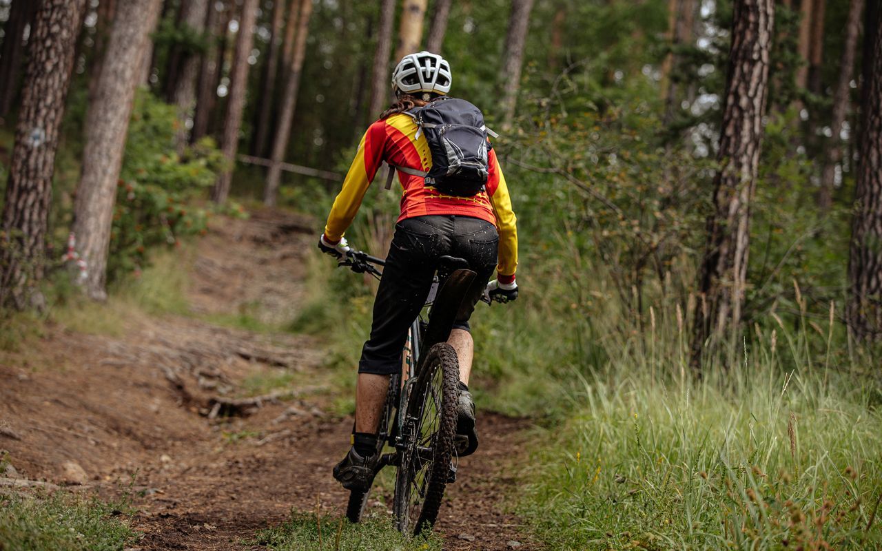 Een koffiemachine zet koffie in een kopje met een bloemenmotief, vlakbij witte lelies in een vaas, macarons en lege kopjes op een tafel.
