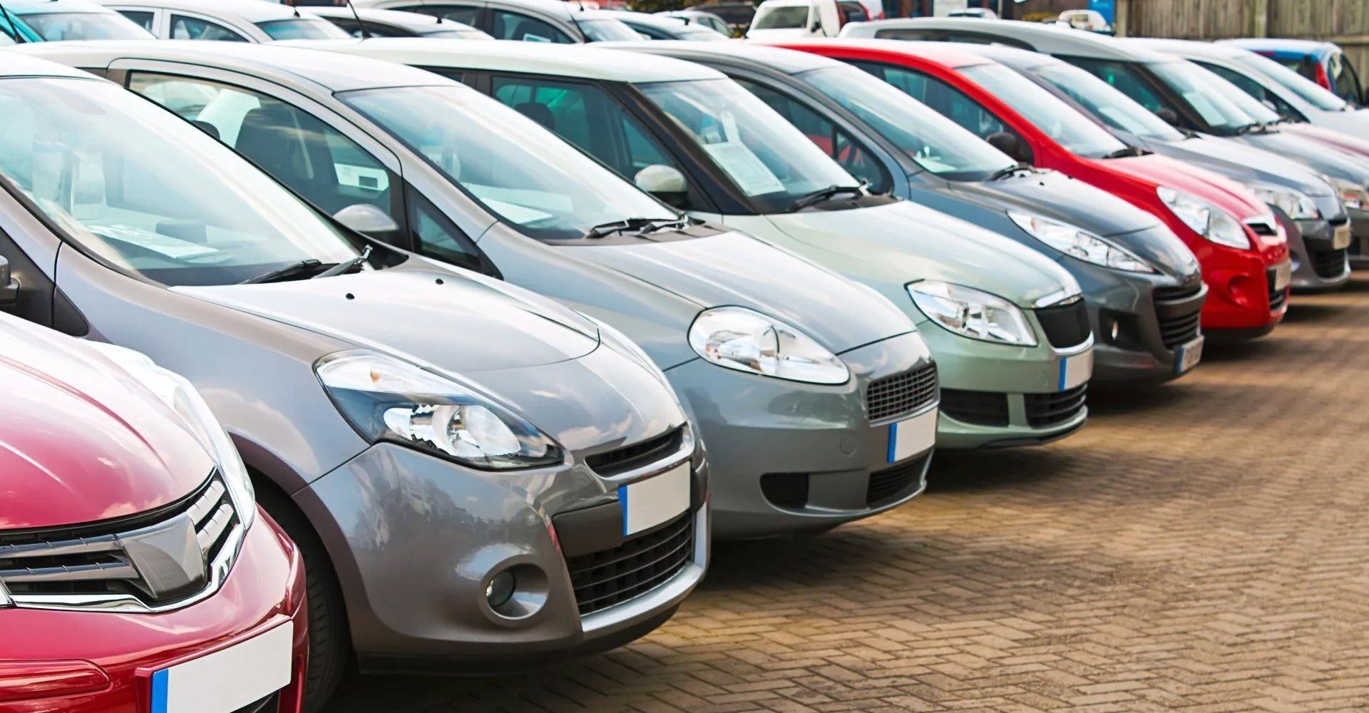 Hände tauschen Autoschlüssel vor einem bordeauxroten Geländewagen aus.