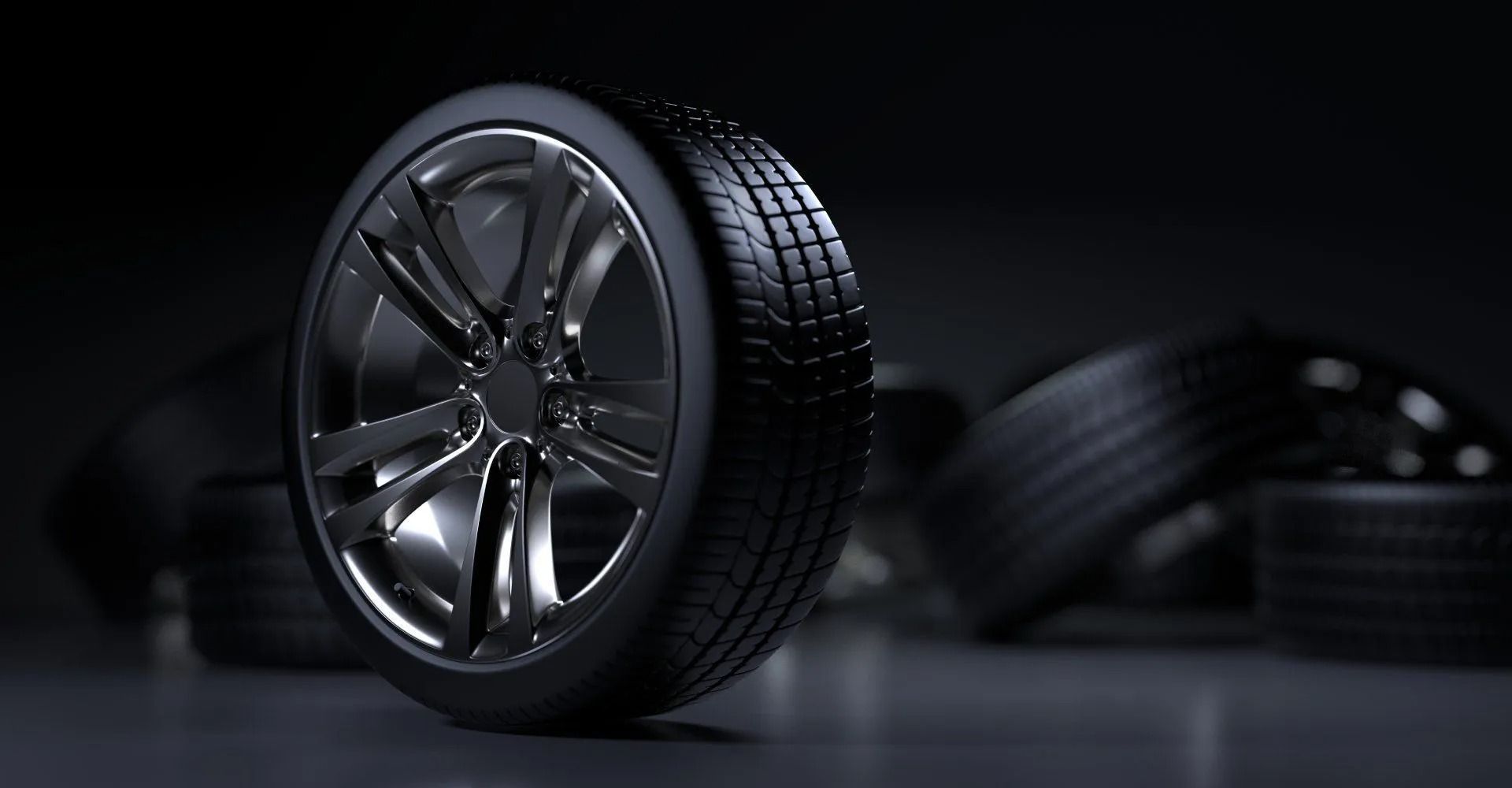 Glänzendes schwarzes Autorad auf einer reflektierenden Oberfläche, im Hintergrund sind verschwommene Reifen zu sehen.