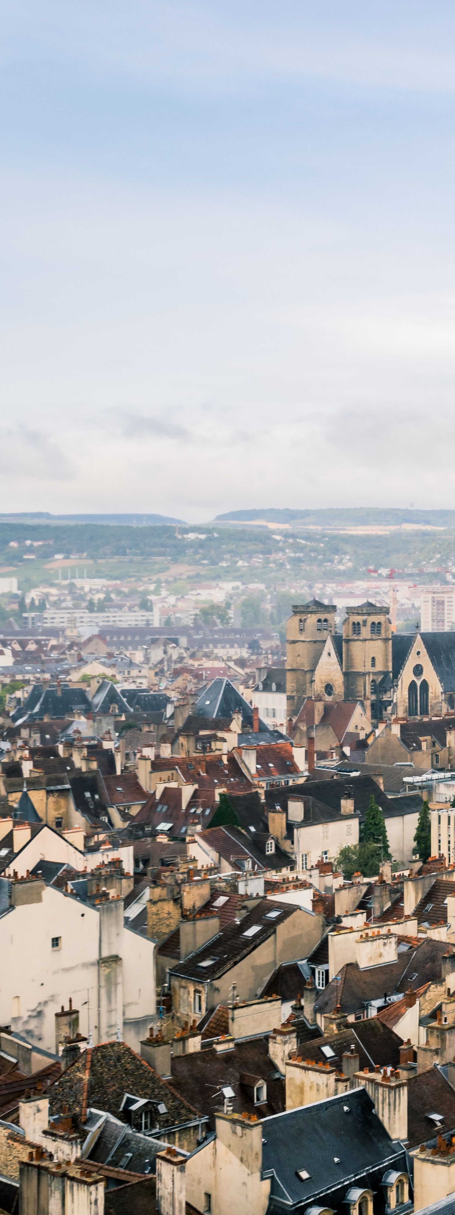 Vue panoramique d'une ville historique aux toits de tuiles et aux clochers d'église sous un ciel nuageux