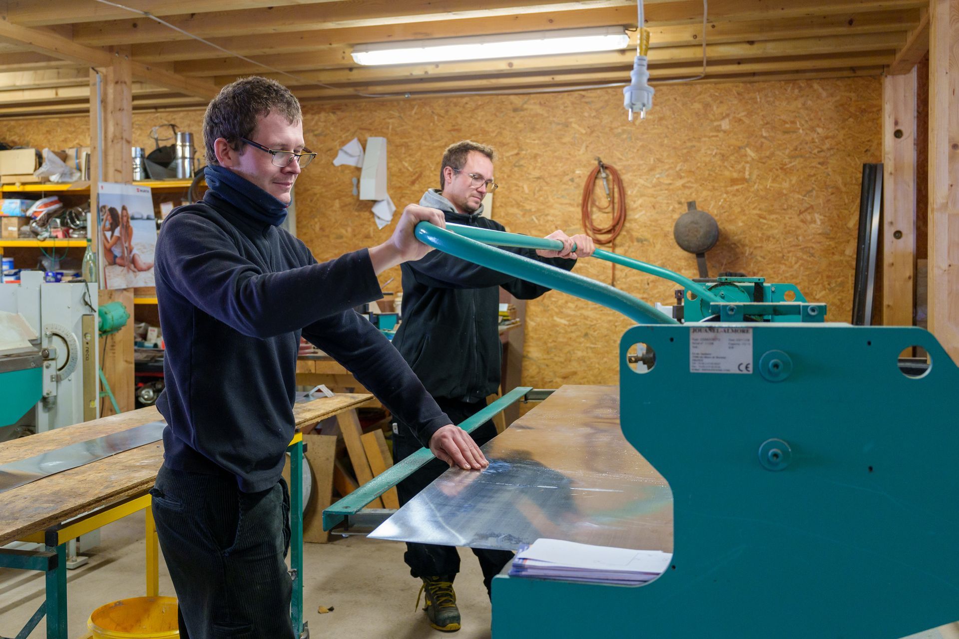 Des personnes manipulent une machine industrielle verte dans un atelier.