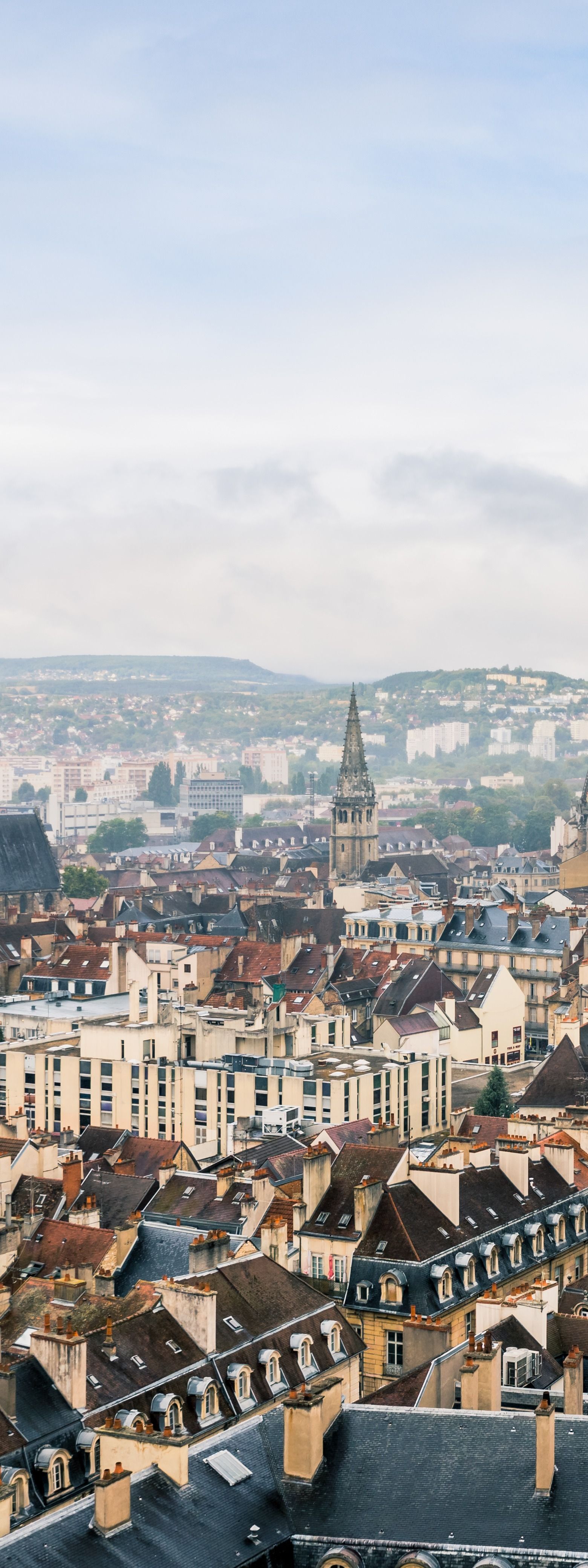 Paysage urbain panoramique composé d'immeubles blancs denses et de clochers d'églises sous un ciel brumeux