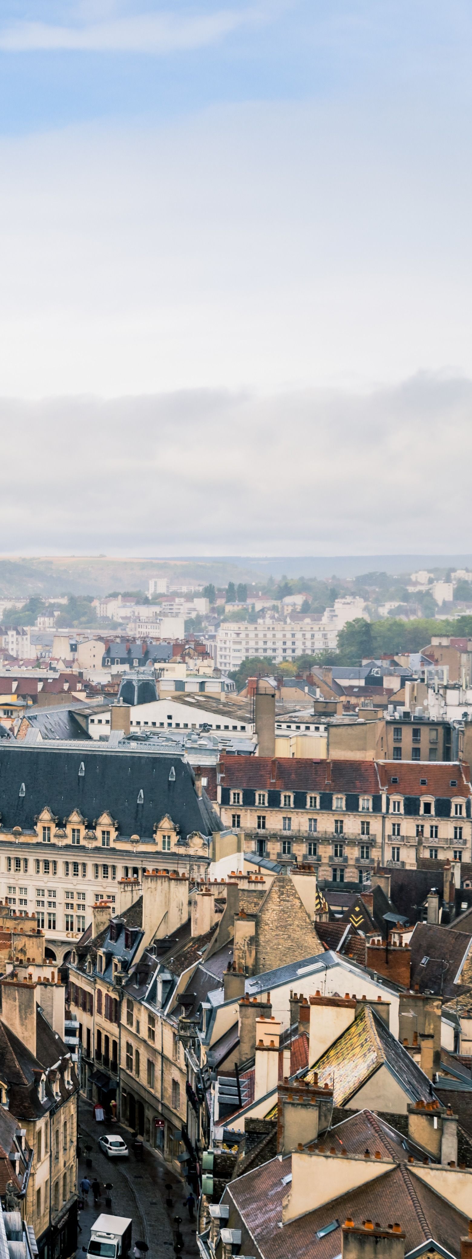 Vue aérienne d'une ville historique aux toits ornés et à l'horizon brumeux sous un ciel pâle