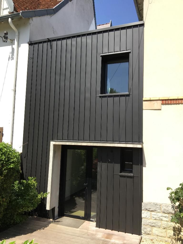 Charpente en bois d'une maison en construction sur fond de ciel bleu.
