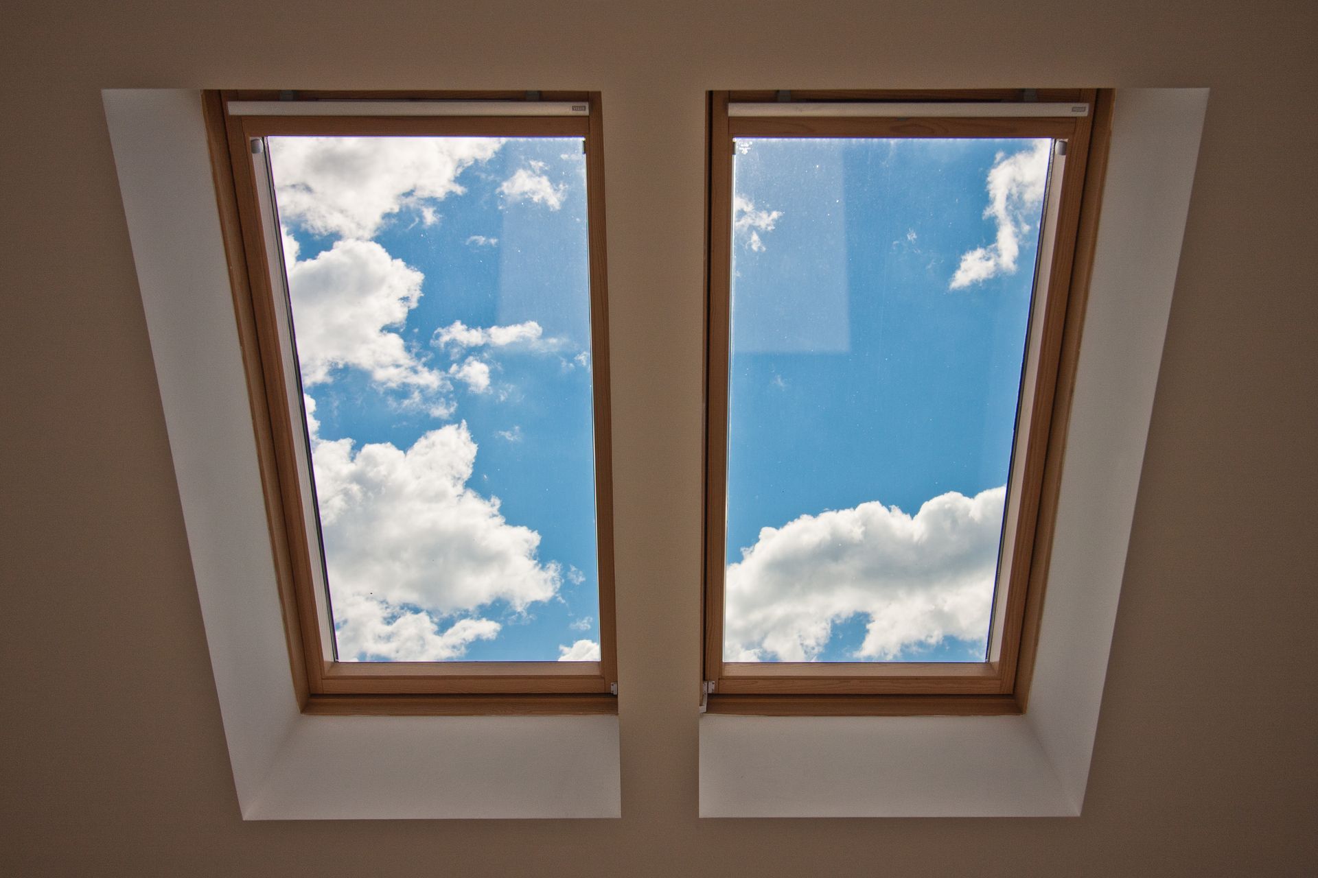 Deux puits de lumière dans le plafond, laissant entrevoir un ciel bleu parsemé de nuages blancs.