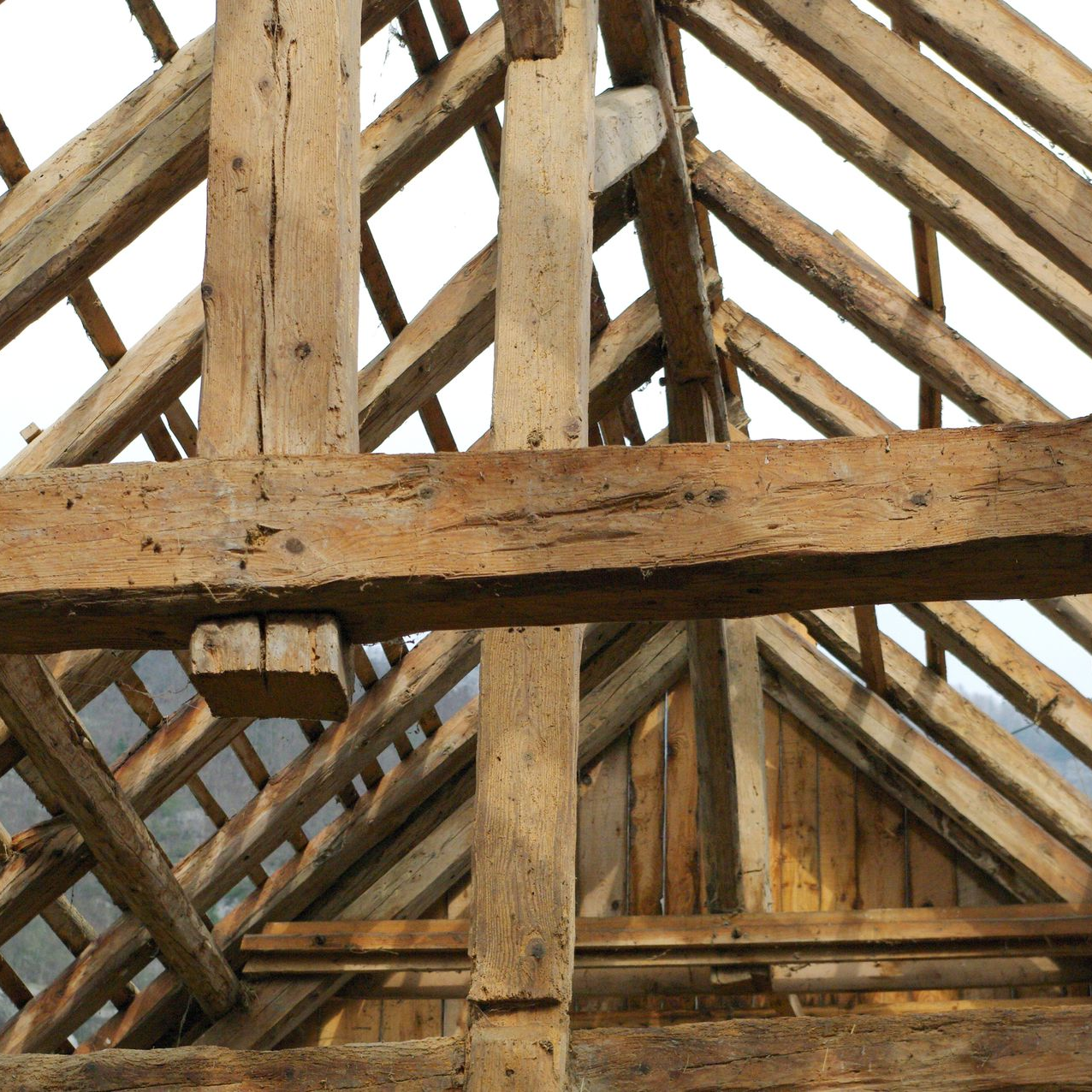Vue intérieure des chevrons de toit en bois apparents dans un grenier ou une grange non aménagée.