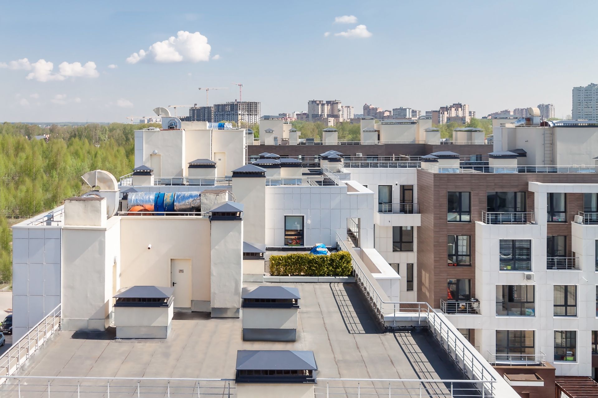 Terrasse sur le toit avec des bâtiments blancs, des équipements de toiture et une silhouette urbaine sous un ciel bleu.