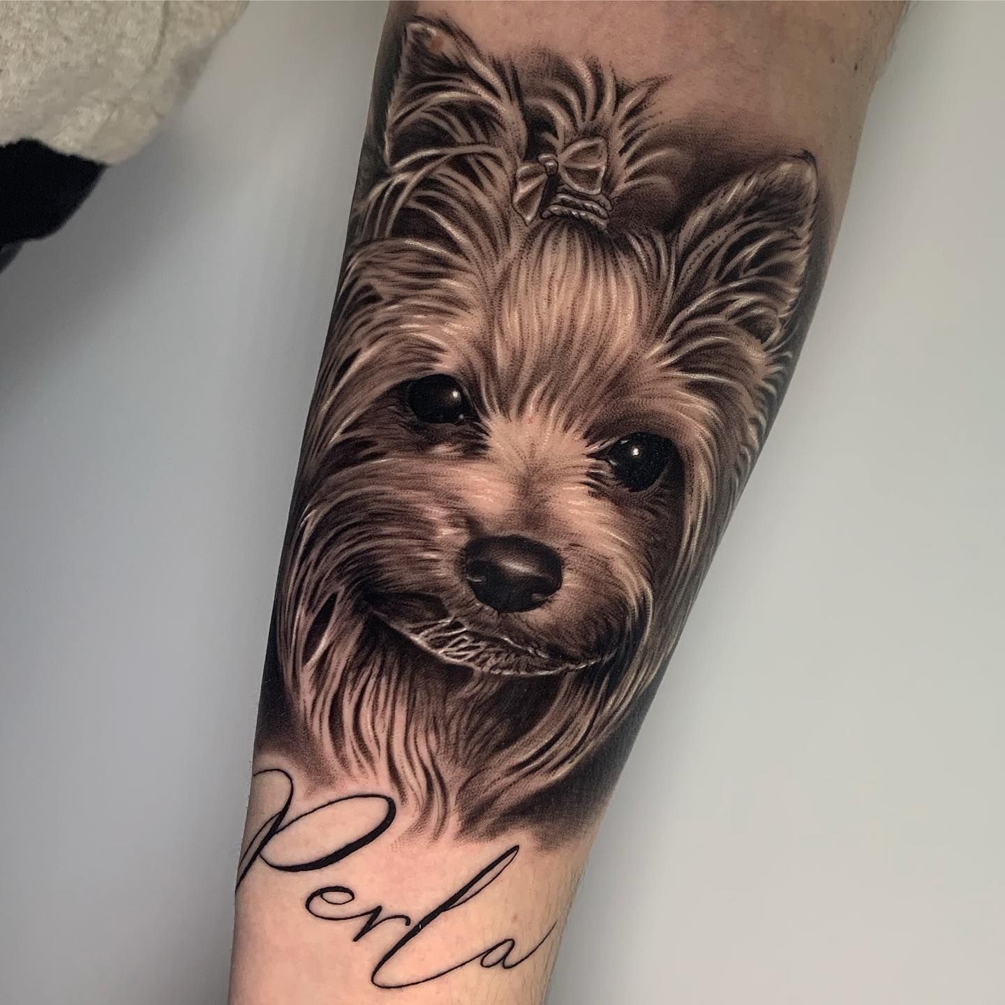 Un tatuaje de un perro con el nombre perla.