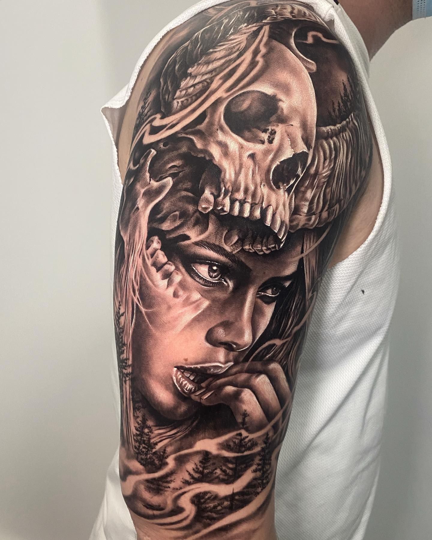 Un hombre tiene un tatuaje de una mujer con una calavera en su brazo.