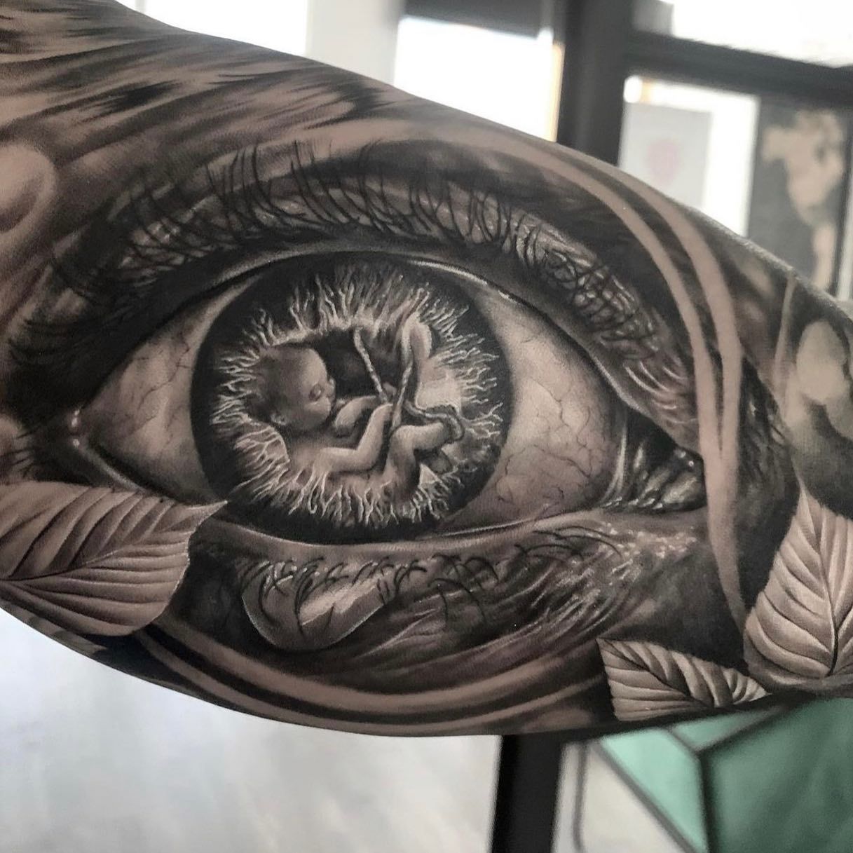 Un tatuaje en blanco y negro de un bebé en el ojo de una mujer.