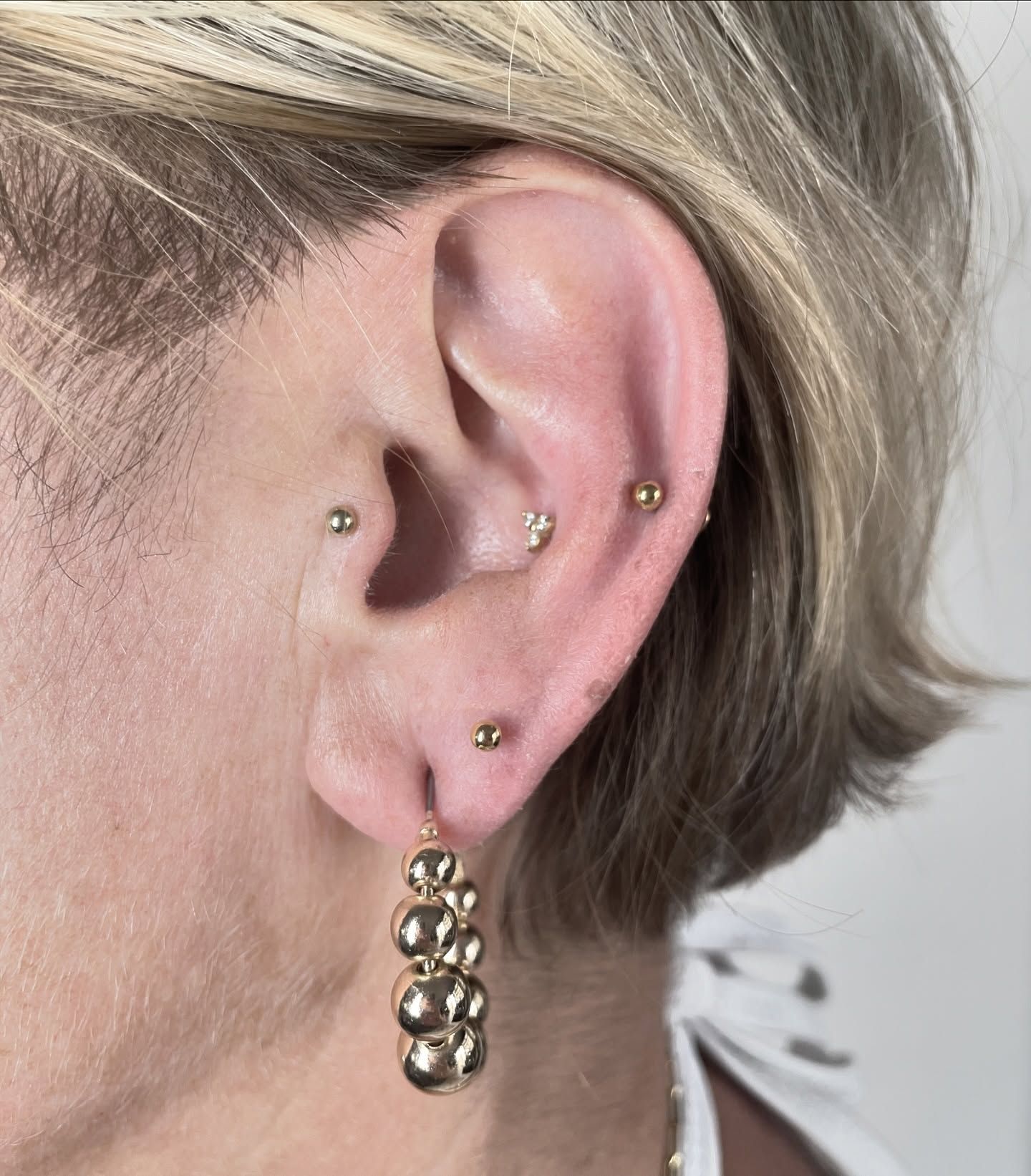 Un primer plano de la oreja de una mujer con múltiples perforaciones.