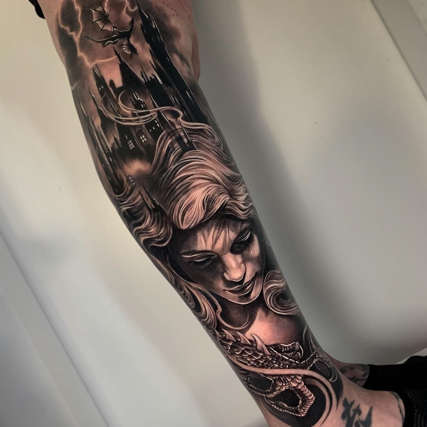 Un tatuaje en blanco y negro de una mujer con un castillo al fondo.