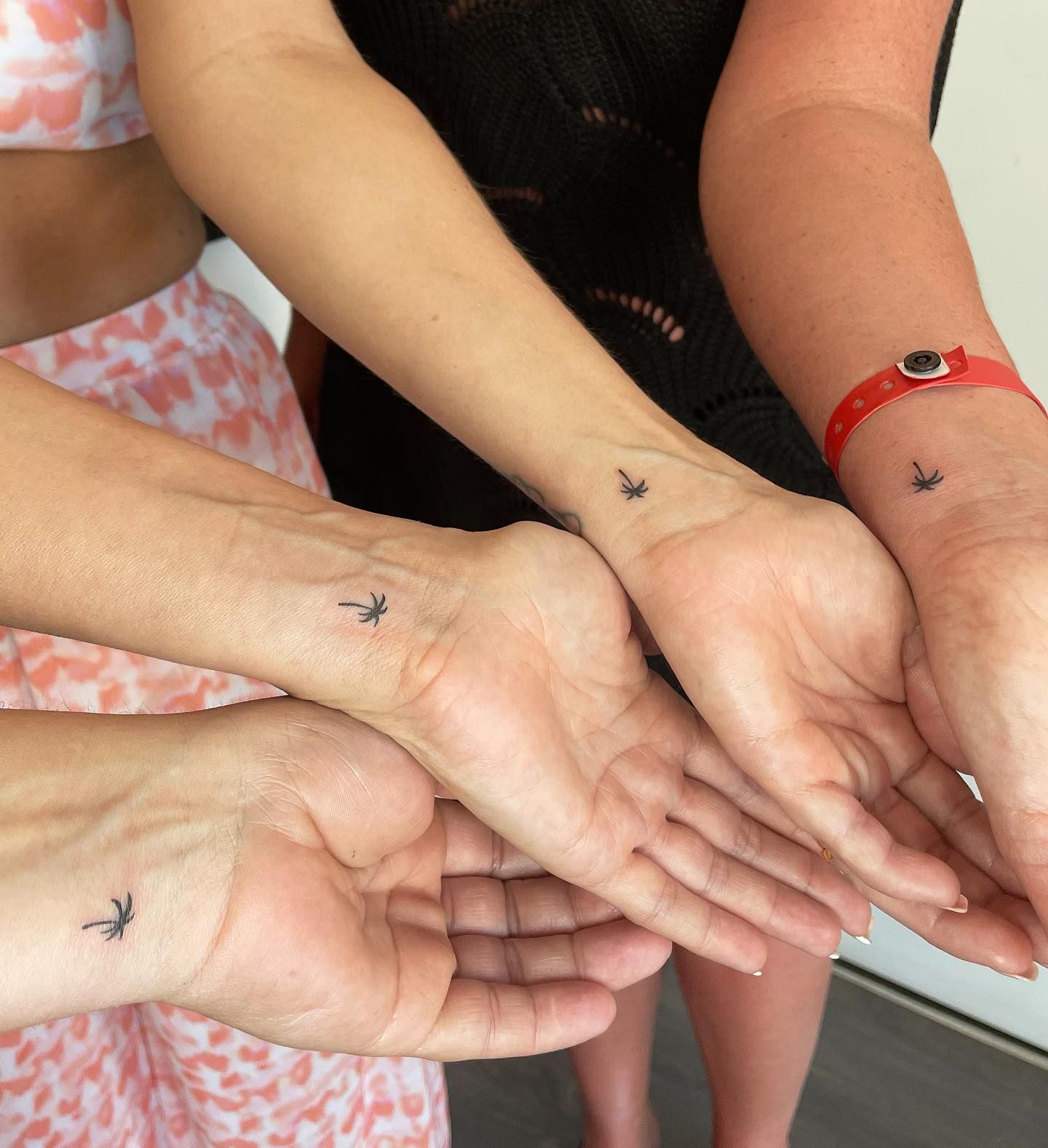 Un grupo de personas con pequeños tatuajes en sus muñecas.