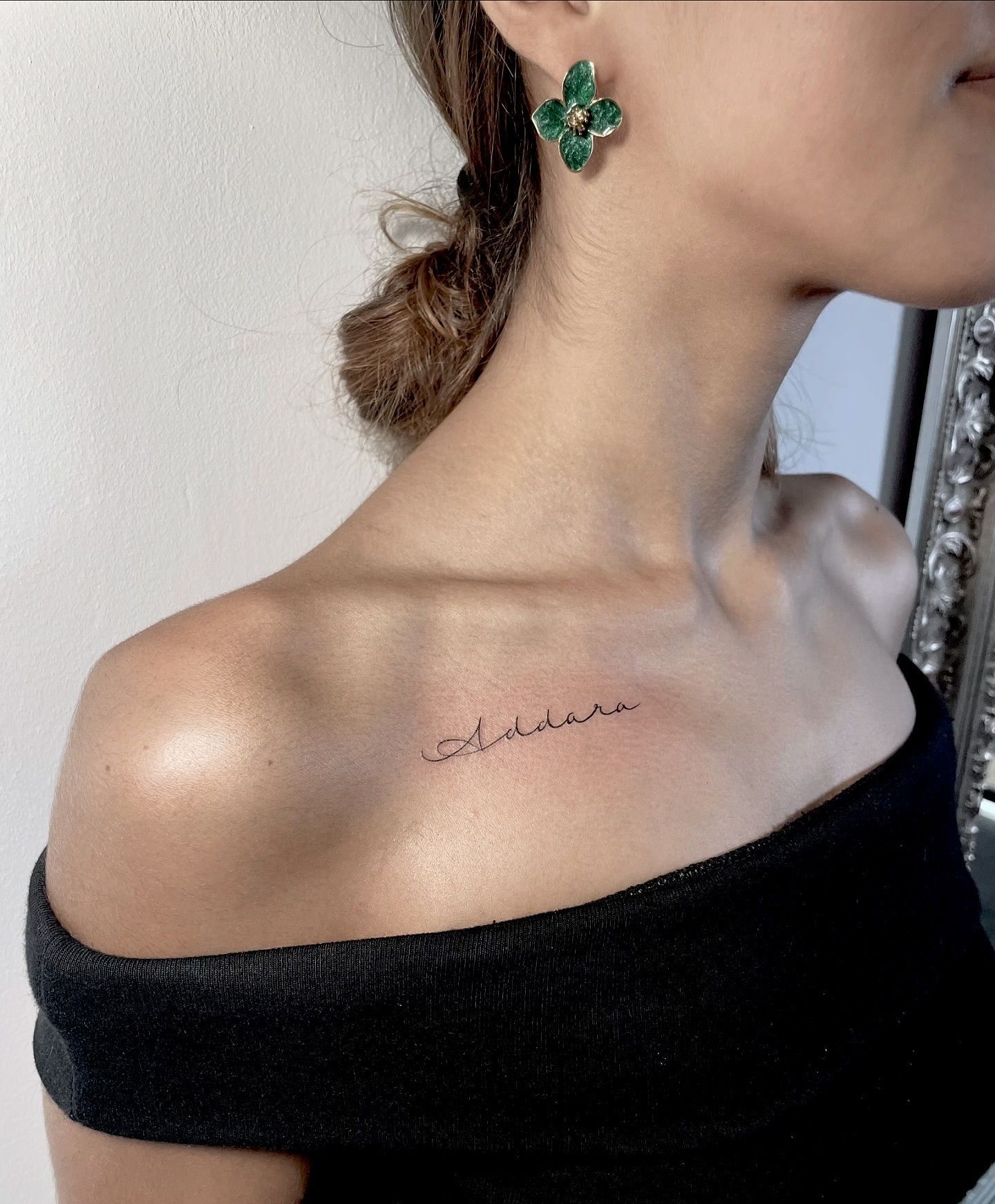 Una mujer con un tatuaje en el hombro y pendientes.