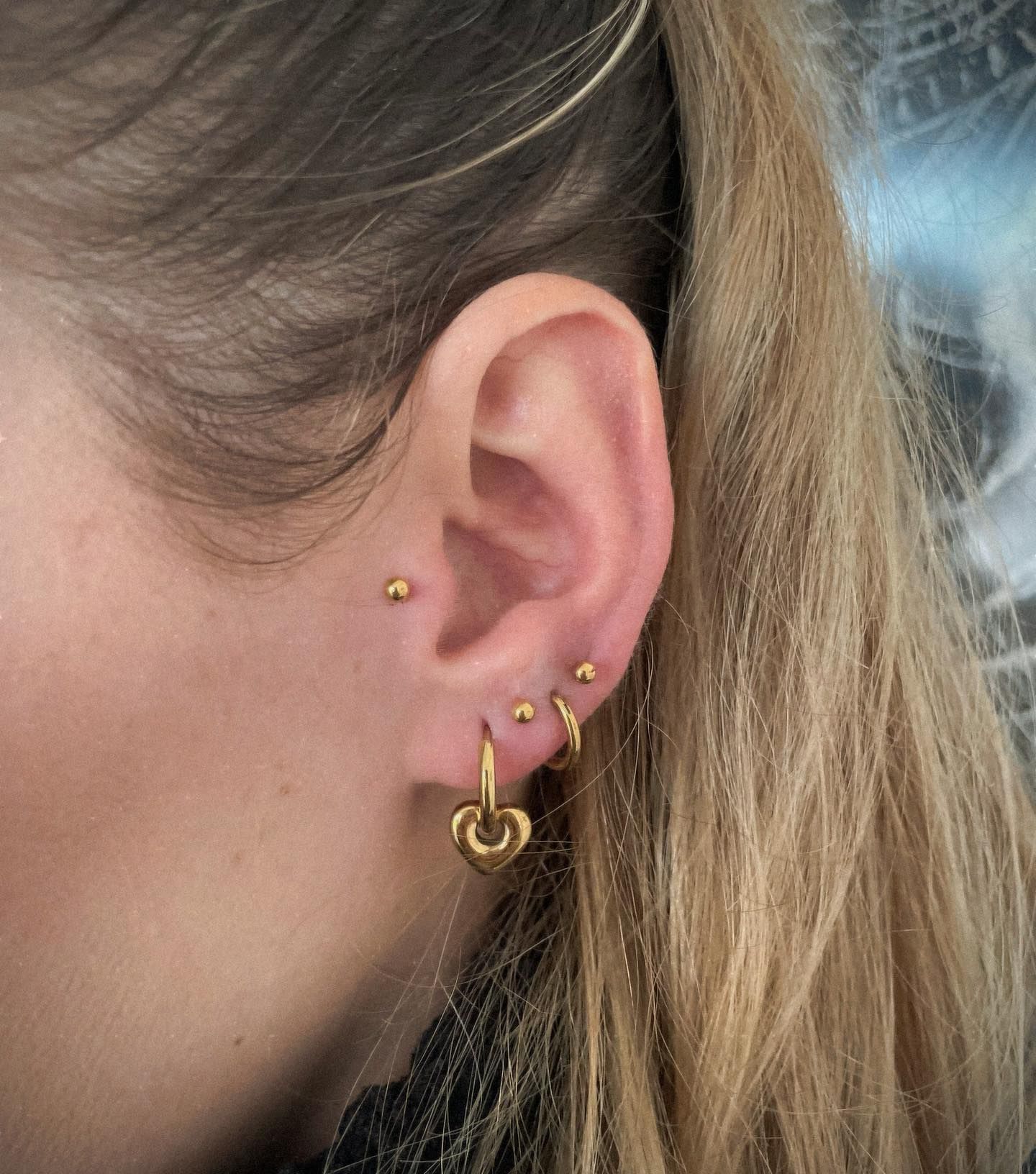 Un primer plano de la oreja de una mujer con múltiples perforaciones.