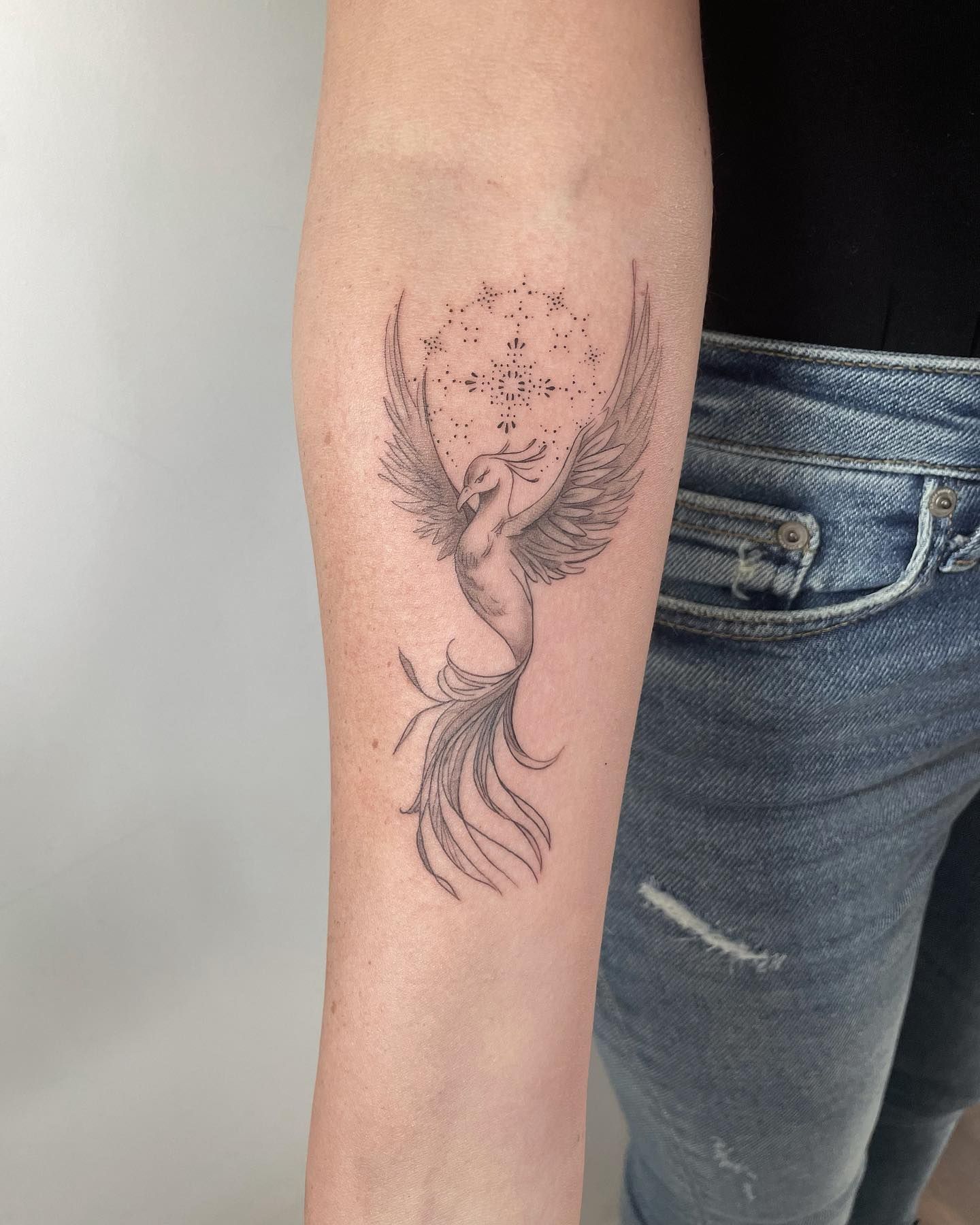 Una mujer tiene un tatuaje de un fénix en su antebrazo.