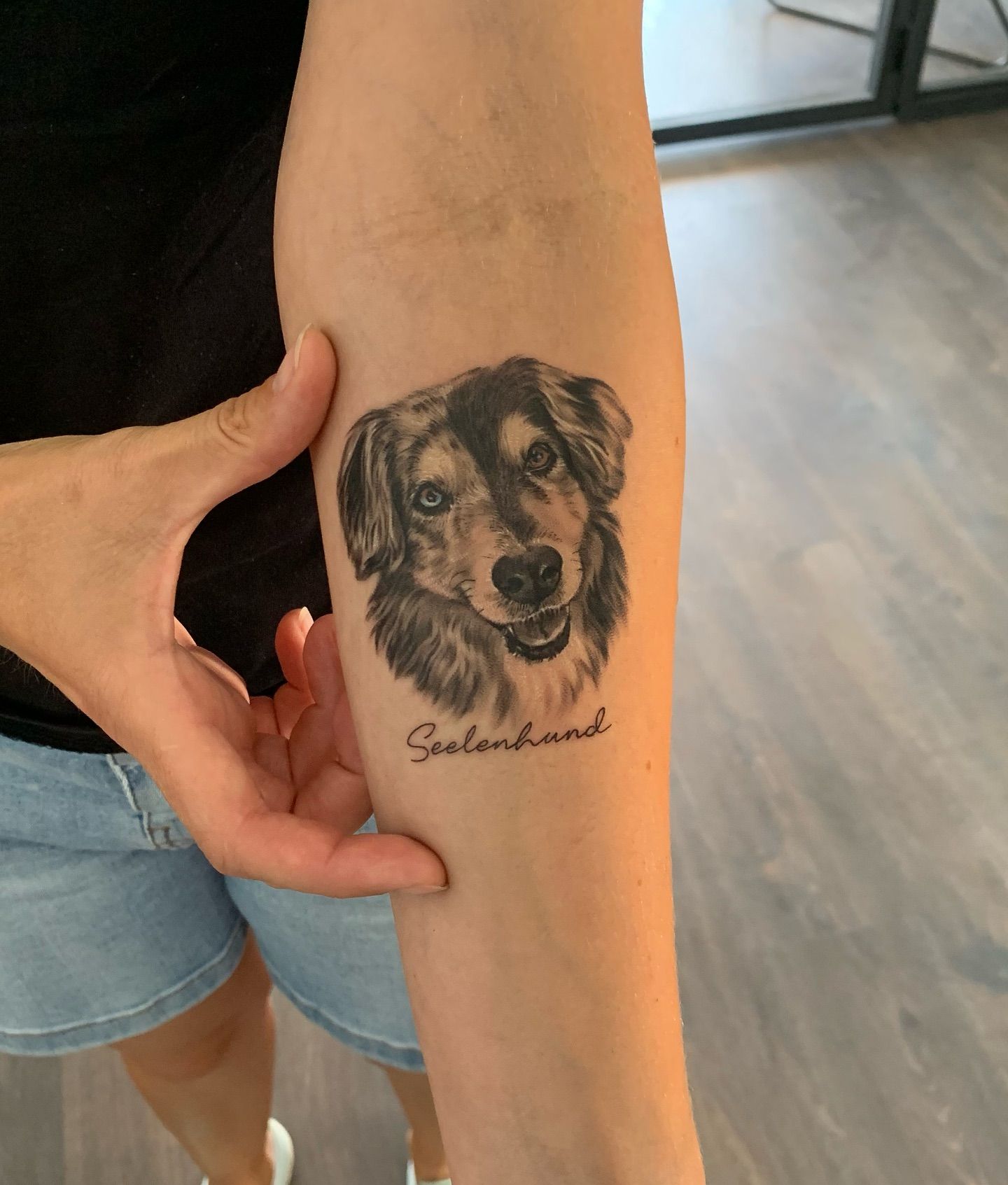 Una mujer tiene un tatuaje de un perro en su antebrazo.