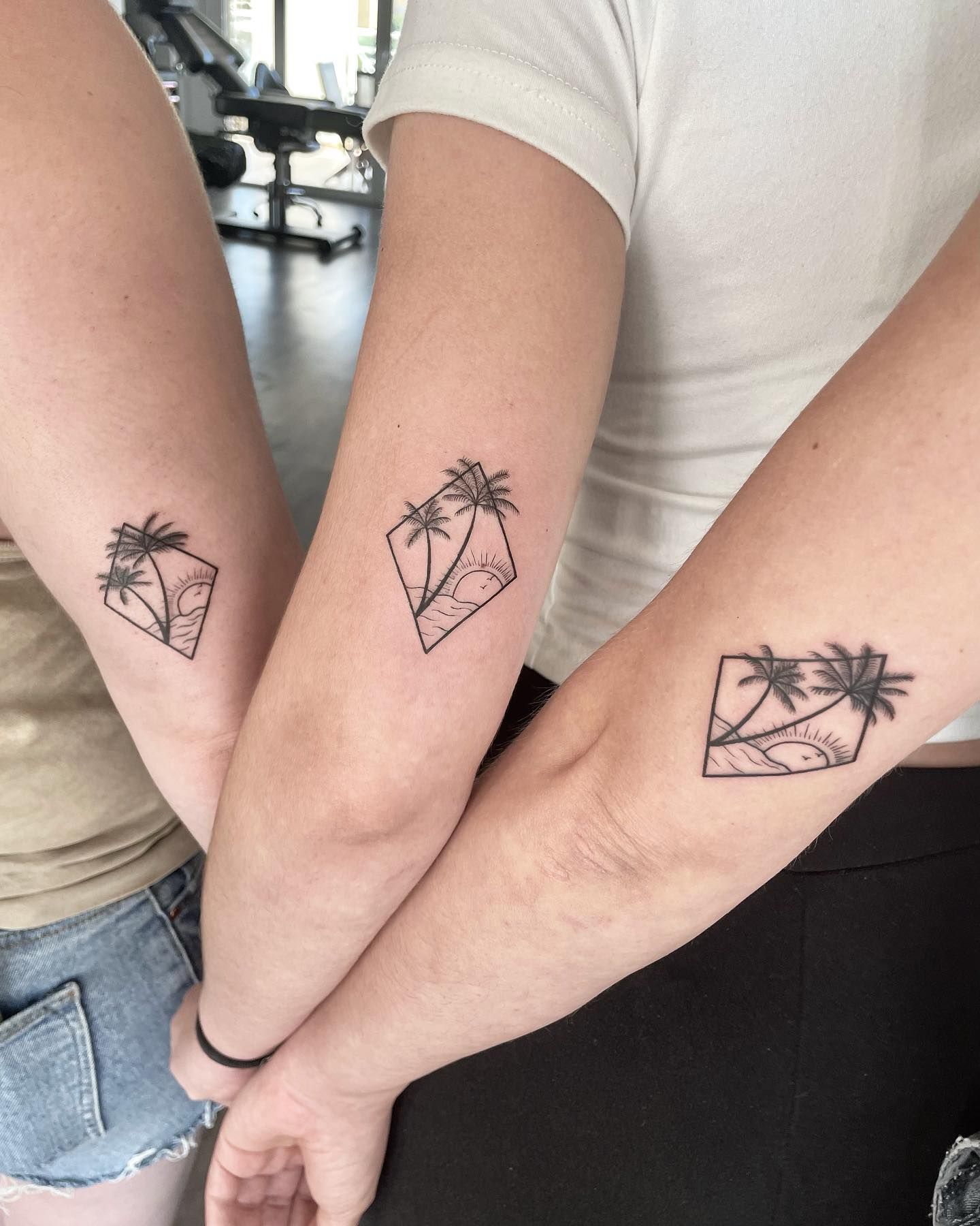 Tres mujeres están paradas una al lado de la otra con tatuajes iguales en sus brazos.