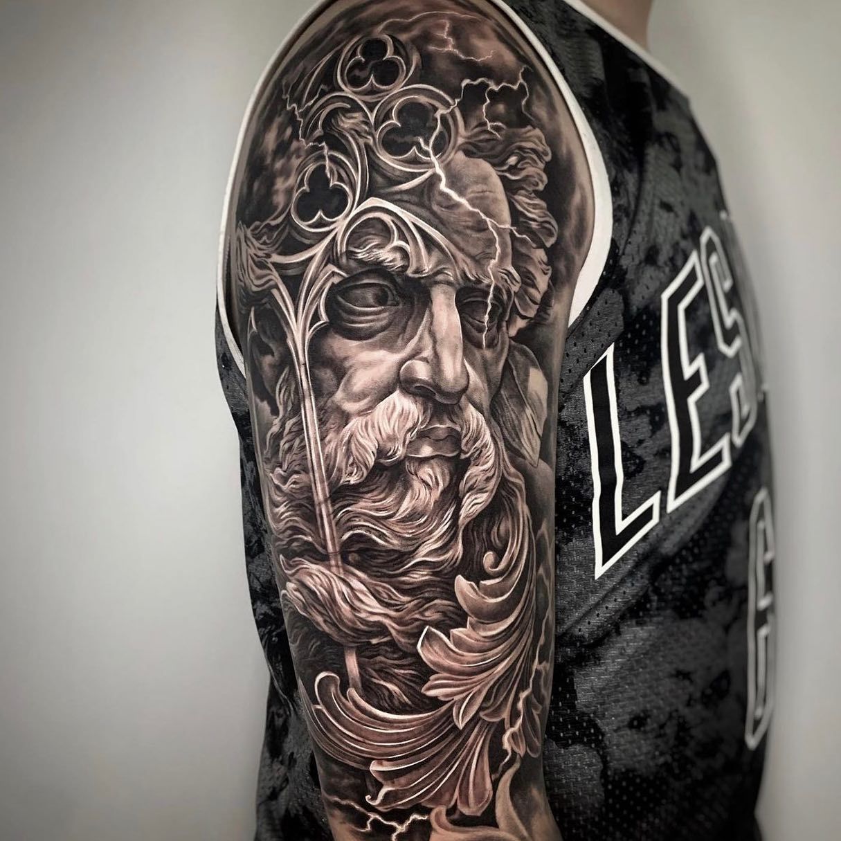 Un tatuaje en blanco y negro de un hombre con barba en el brazo.