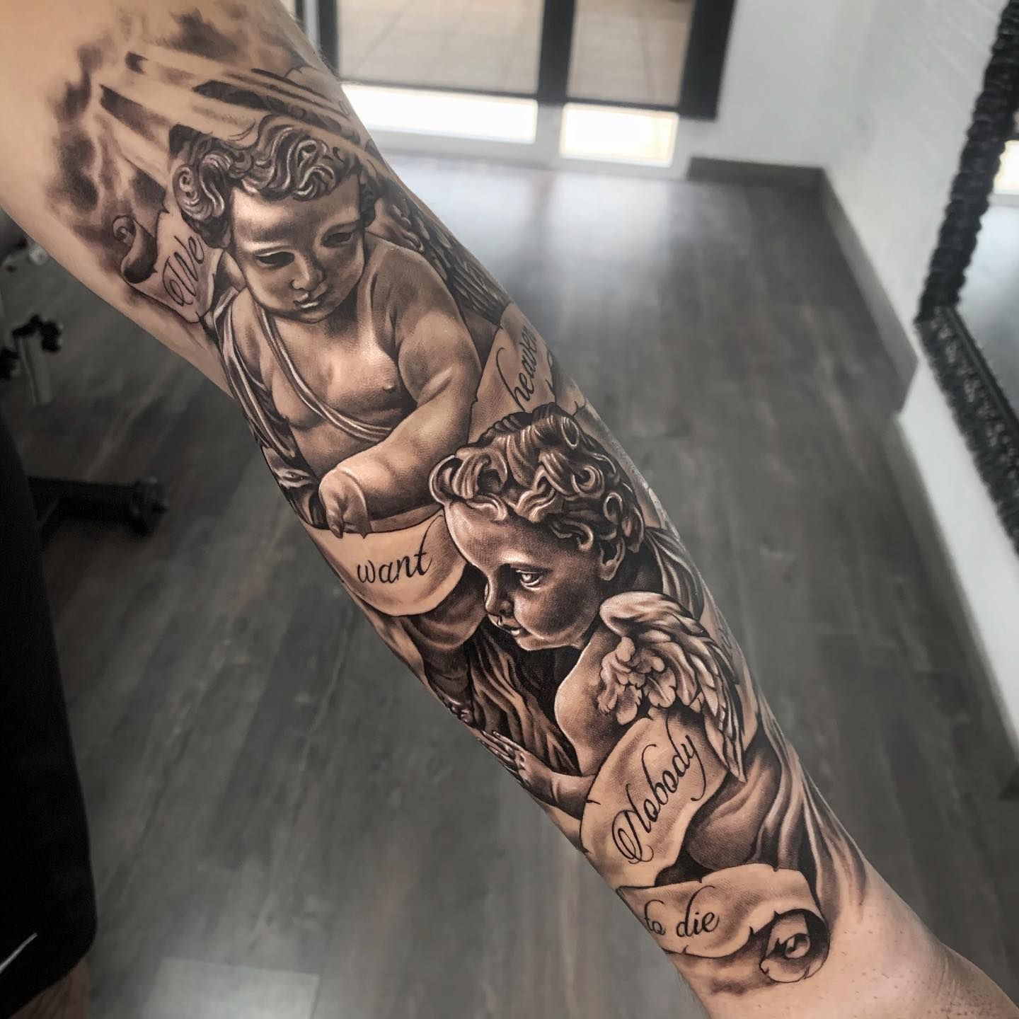 Una persona tiene un tatuaje de dos querubines en su antebrazo.