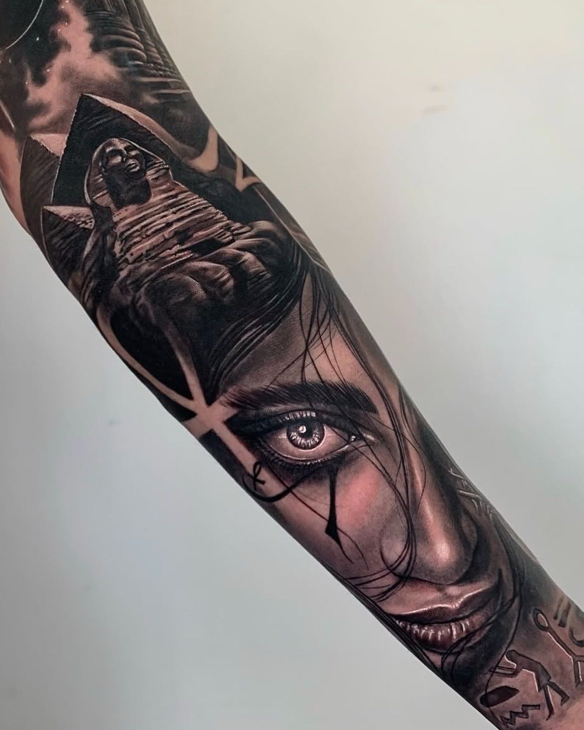 Un tatuaje de la cara de una mujer con una pirámide al fondo.