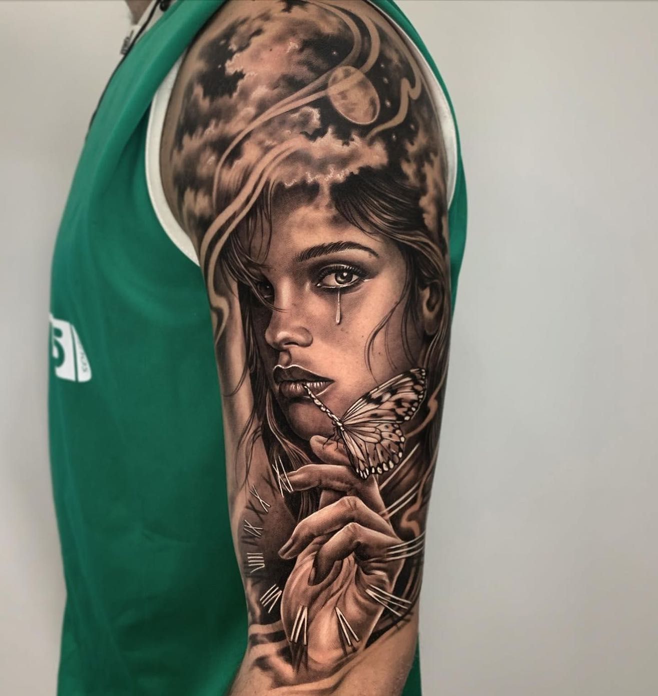 Un hombre tiene un tatuaje de una mujer sosteniendo una mariposa en su brazo.