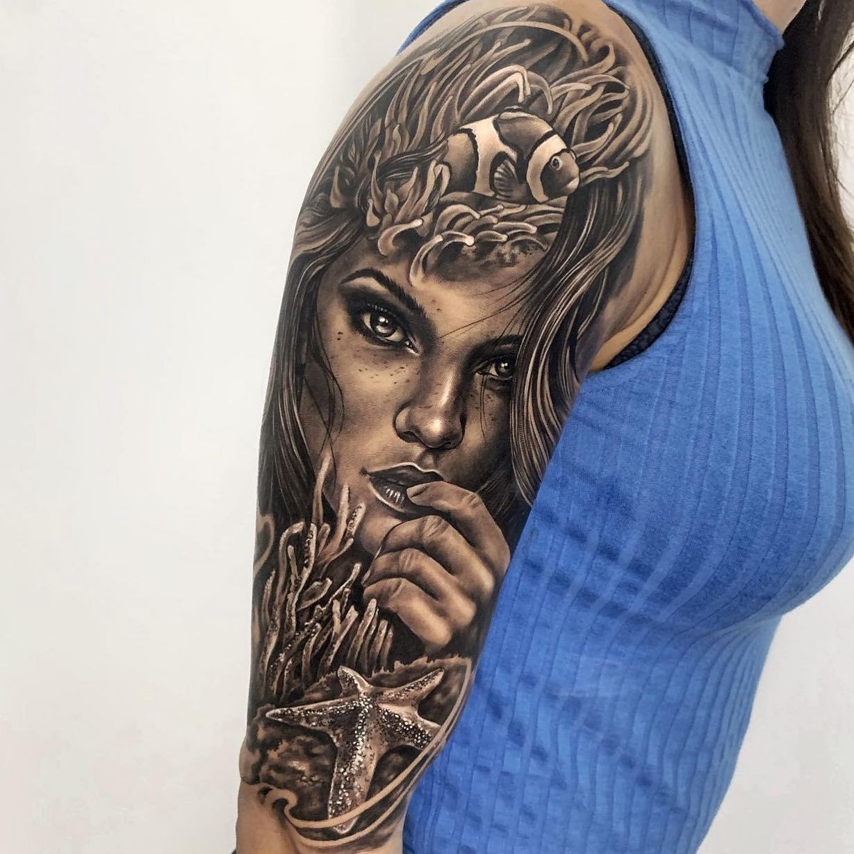 Una mujer tiene un tatuaje de la cara de una mujer en su brazo.