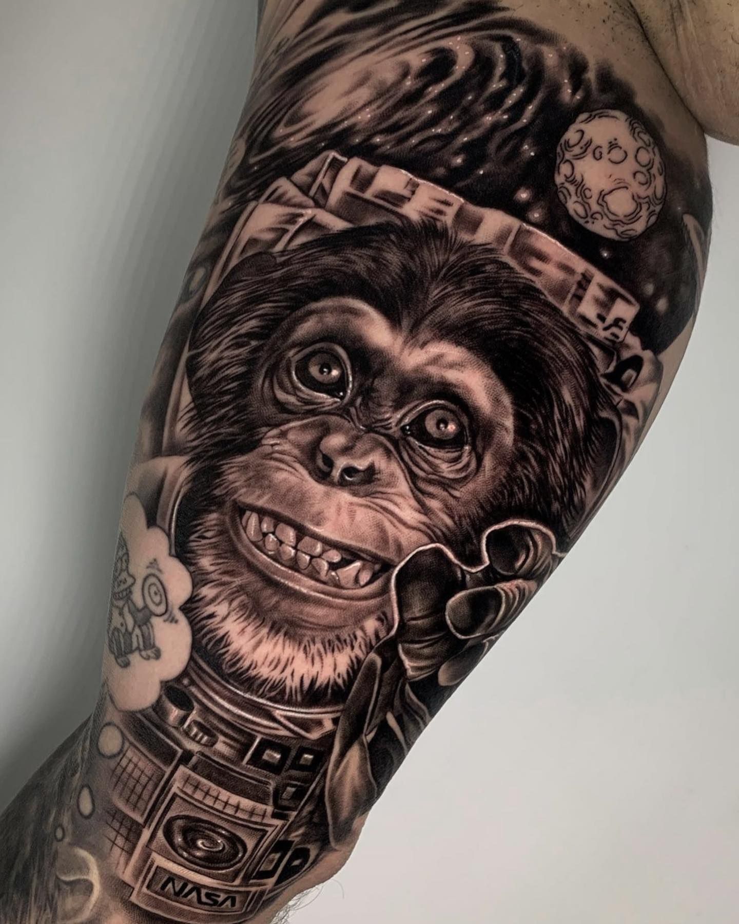 Un tatuaje en blanco y negro de un chimpancé en el brazo de un hombre.