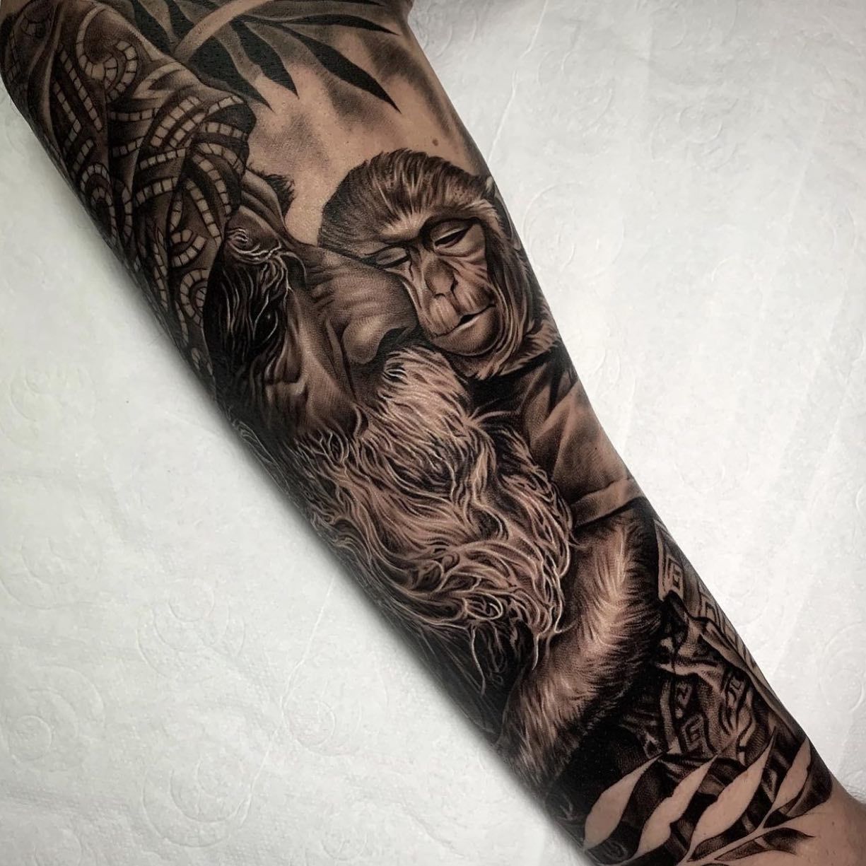 Un tatuaje en blanco y negro de un mono en el brazo de una persona.